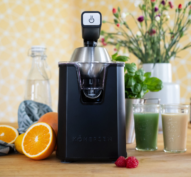Wyciskarka Kohersen stoi na blacie kuchennym, obok szklanki z wyciśniętym sokiem 