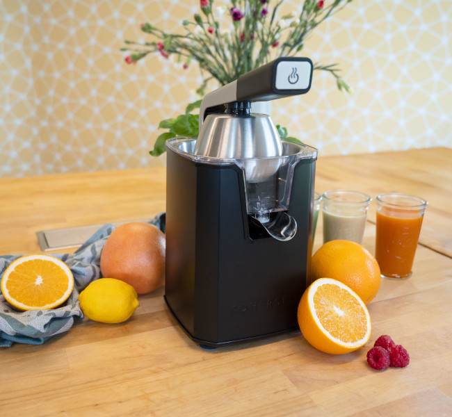 Wyciskarka Kohersen stoi na blacie kuchennym, obok przekrojone na pół cytrusy